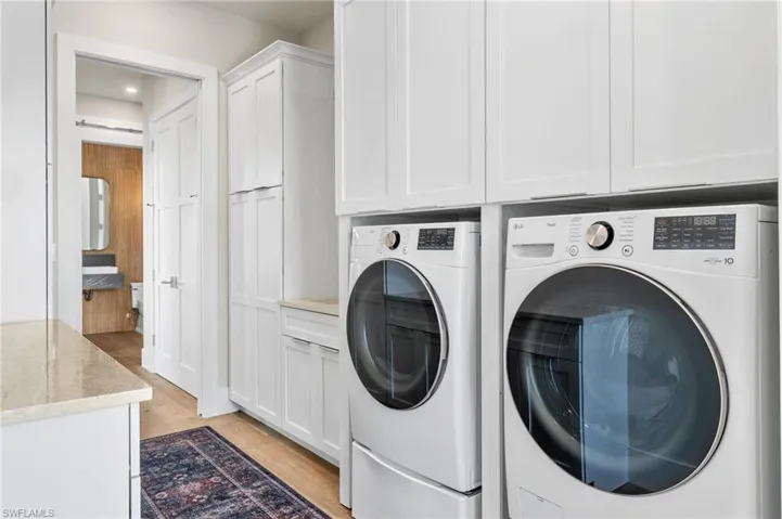 Washroom featuring light wood-style flooring, cabinet space, and washer and clothes dryer