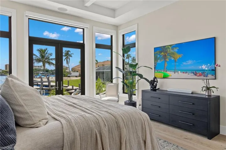 Bedroom with light wood-style floors, a water view, and access to exterior