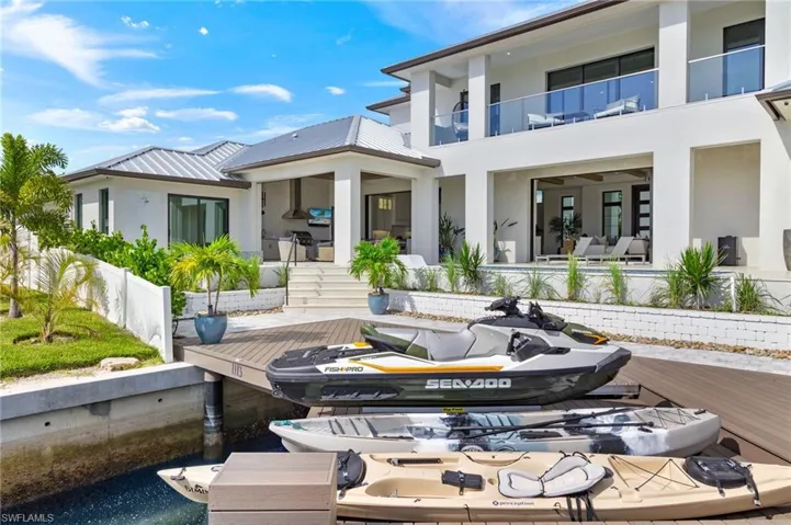 Rear view of property with stucco siding, a balcony, a patio area, and a water view