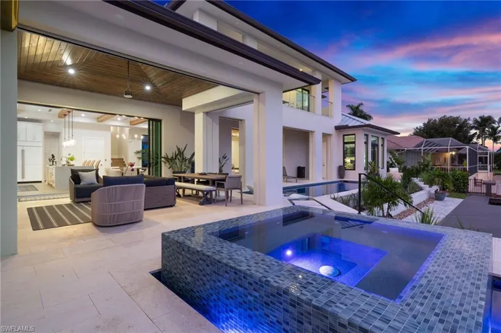 Pool at dusk with a patio, an in-ground hot tub, outdoor dining space, and an outdoor pool