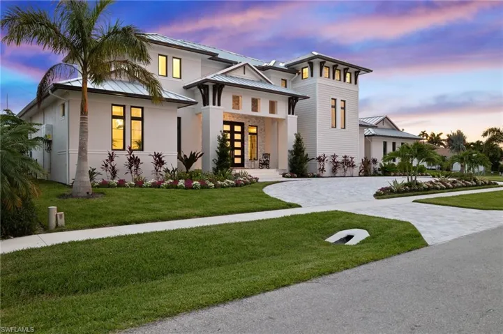View of front of house featuring a front yard, decorative driveway, a metal roof, and french doors