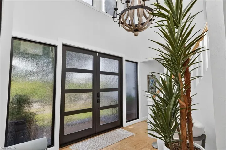 Foyer entrance featuring wood finished floors, french doors, and a chandelier