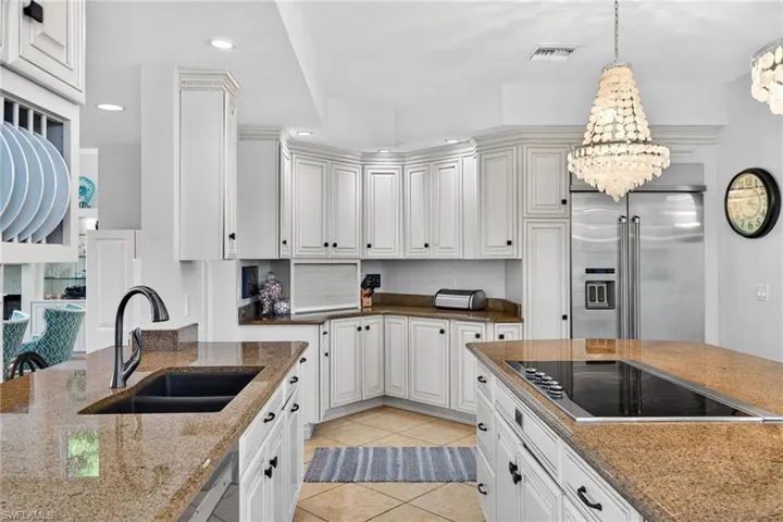Kitchen featuring appliances with stainless steel finishes, recessed lighting, light tile patterned flooring, decorative light fixtures, and light stone counters