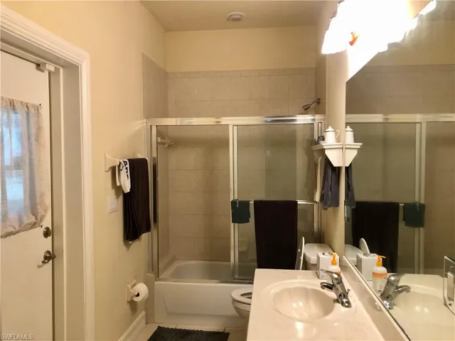 Full bathroom featuring vanity, bath / shower combo with glass door, and tile patterned floors
