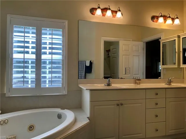 Full bathroom with double vanity and a tub with jets