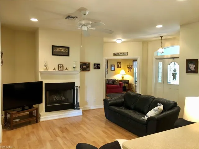 Living room with recessed lighting, light wood-type flooring, ceiling fan, and a fireplace with raised hearth