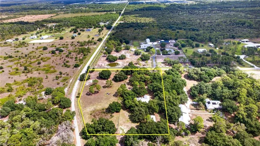 Expansive land parcel featuring a mix of mature trees and cleared areas, bordered by a paved road