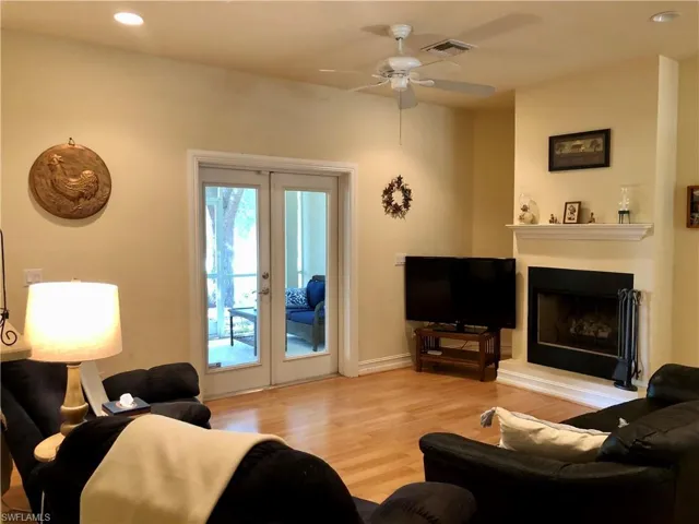 Living room with recessed lighting, french doors, light wood-type flooring, a ceiling fan, and a fireplace with raised hearth