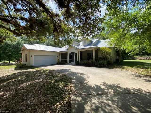 View of front of house featuring a garage, concrete driveway, a standing seam roof, a front yard, and stucco siding