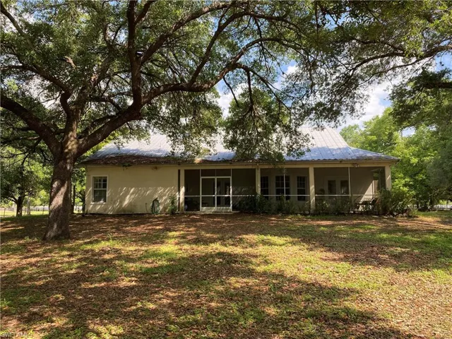 Rear view of property featuring a yard, a sunroom, a metal roof, and stucco siding