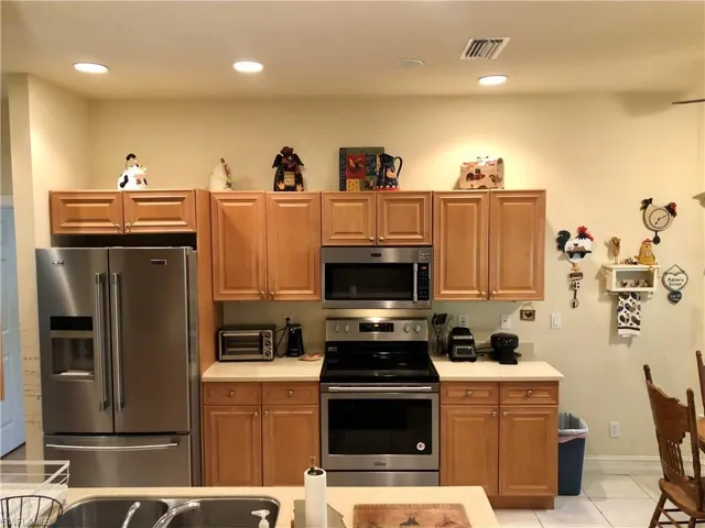 Kitchen featuring stainless steel appliances, wood finish cabinetry, light tile patterned floors, and recessed lighting