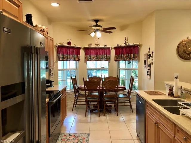 Kitchen with black appliances, ceiling fan, light tile patterned floors, wood finish cabinetry, and plenty of natural light
