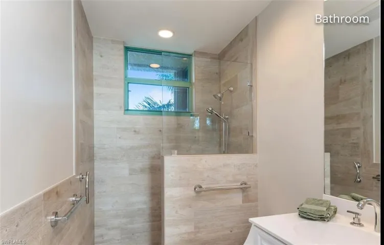 Bathroom with tiled shower and vanity