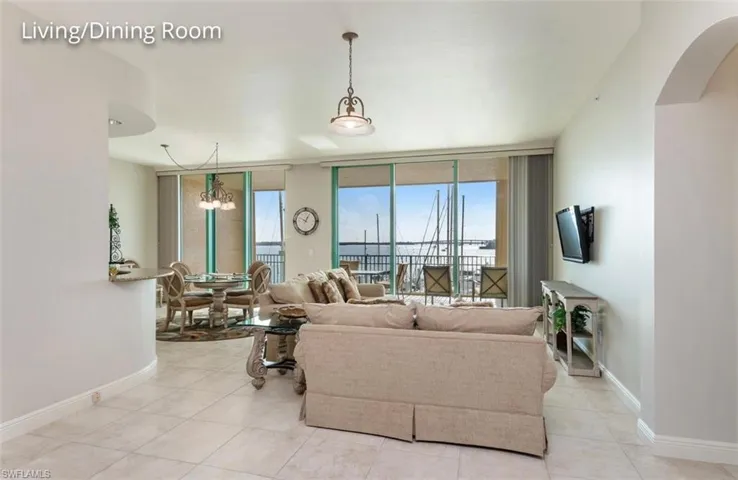Tiled living area featuring arched walkways, a notable chandelier, and baseboards