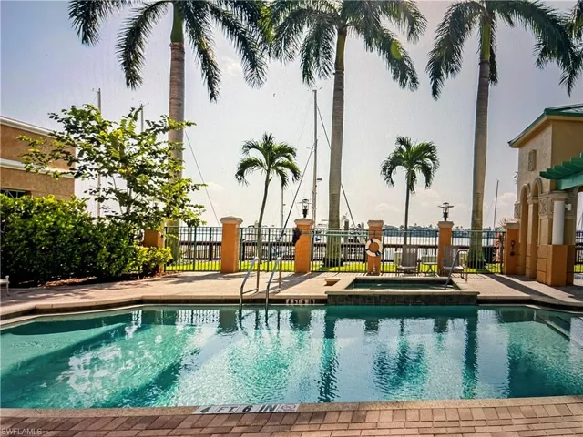 View of swimming pool featuring a community hot tub and fence