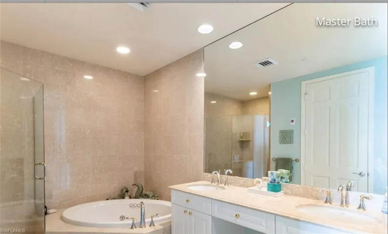 Full bath with a stall shower, a sink, and a jetted tub