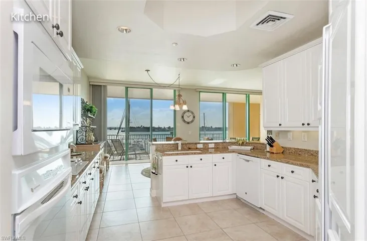 Kitchen featuring visible vents, light tile patterned flooring, white cabinets, white appliances, and a peninsula