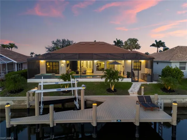 Back of property with boat lift, a lanai, a yard, an outdoor pool, and a patio area