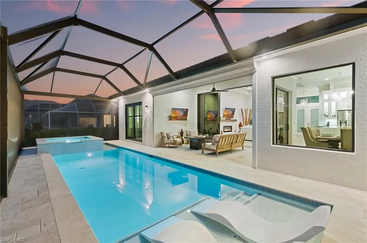 Pool at dusk with a patio, outdoor lounge area, a lanai, and a pool with connected hot tub