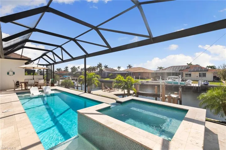 View of pool featuring a patio, a lanai, a water view, a residential view, and a dock