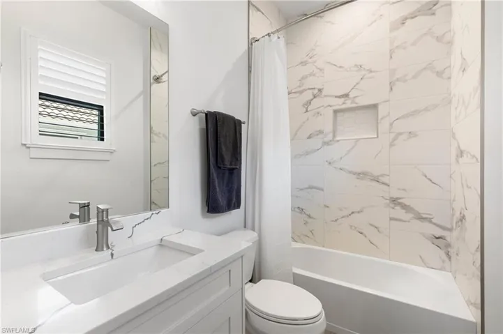 Bathroom with vanity, shower / bath combo with shower curtain, and toilet