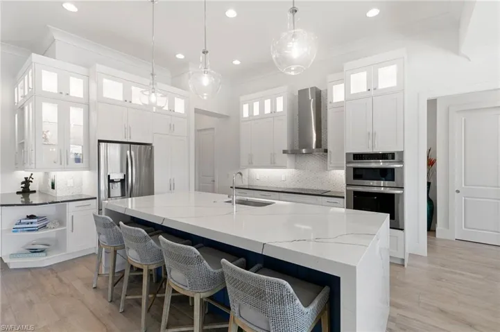 Kitchen with decorative backsplash, appliances with stainless steel finishes, ornamental molding, a sink, and wall chimney exhaust hood