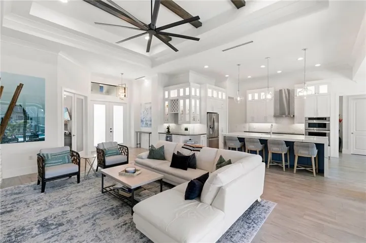 Living room with recessed lighting, french doors, light wood-type flooring, a raised ceiling, and crown molding