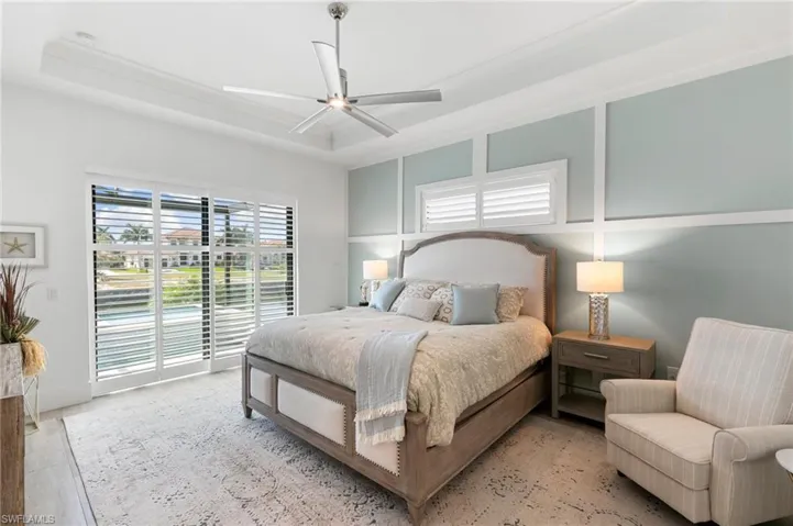 Bedroom with access to outside, a tray ceiling, and a ceiling fan