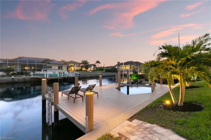 Dock area with a water view, boat lift, and a residential view