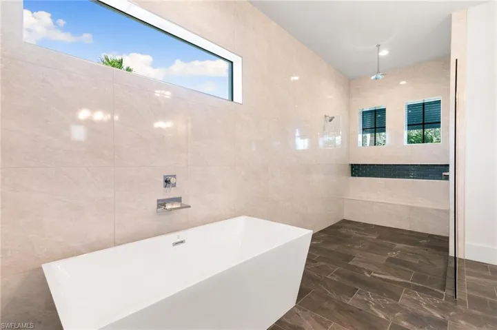 Bathroom with a freestanding bath, tiled shower, and tile walls