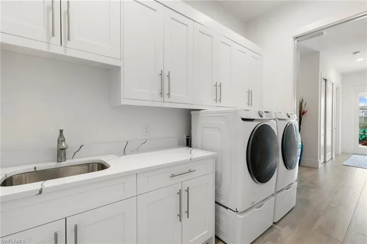 Washroom with light wood finished floors, cabinet space, visible vents, washing machine and dryer, and a sink