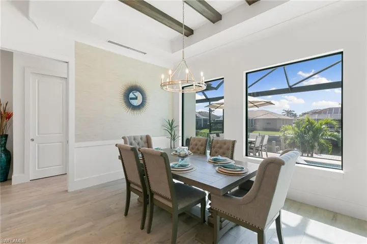 Dining area featuring a wainscoted wall, a wealth of natural light, beam ceiling, and light wood-style floors