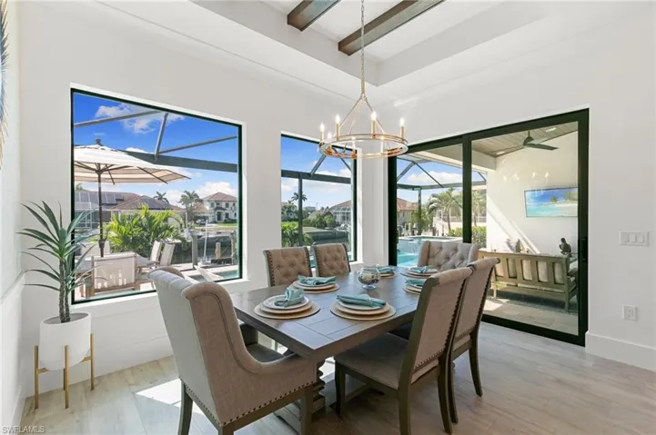 Dining room featuring a notable chandelier, a sunroom, baseboards, light wood-type flooring, and beam ceiling
