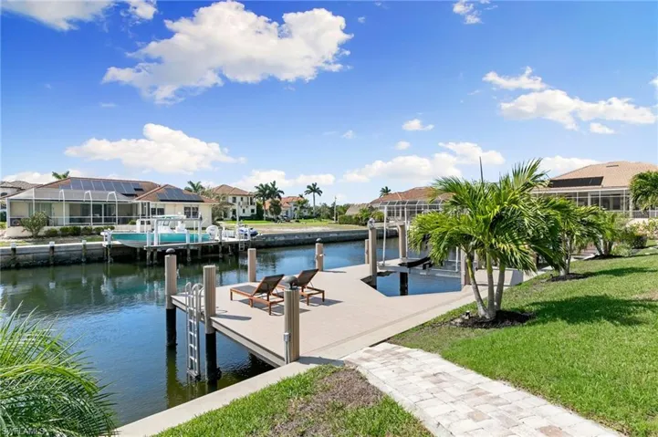 Dock area featuring a water view, boat lift, a residential view, and a yard