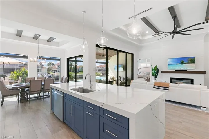 Kitchen with open floor plan, stainless steel dishwasher, a sink, and a glass covered fireplace