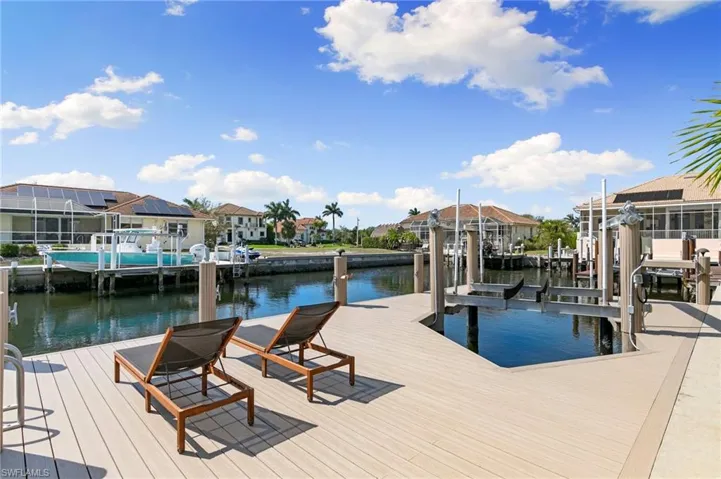 Dock area with a water view, boat lift, and a residential view