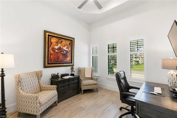 Home office featuring baseboards, light wood-style flooring, and a ceiling fan