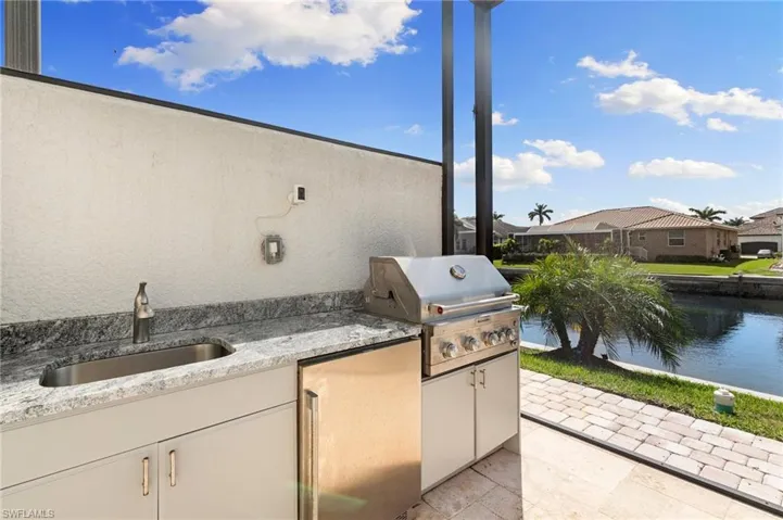 View of patio / terrace with an outdoor kitchen, grilling area, a sink, and a water view