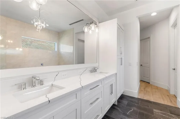 Full bathroom with a walk in shower, double vanity, a sink, and baseboards