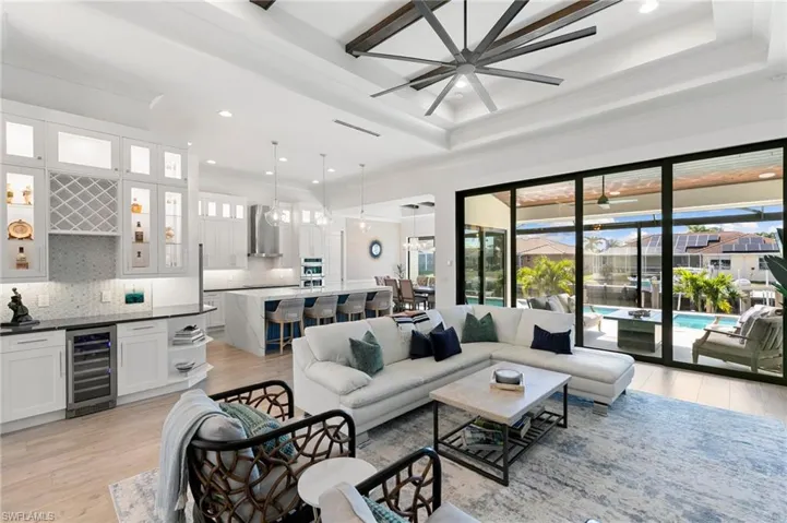 Living room with light wood-type flooring, wine cooler, and a raised ceiling