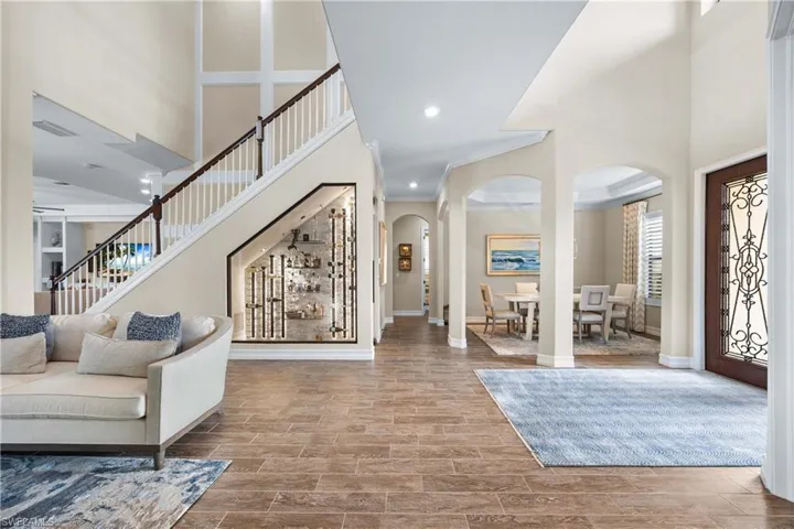 Foyer entrance with arched walkways, a high ceiling, wood tiled floors, stairs, and recessed lighting