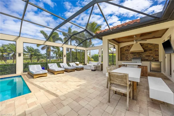 View of patio / terrace featuring exterior kitchen, a sunroom, ceiling fan, a lanai, and an outdoor pool