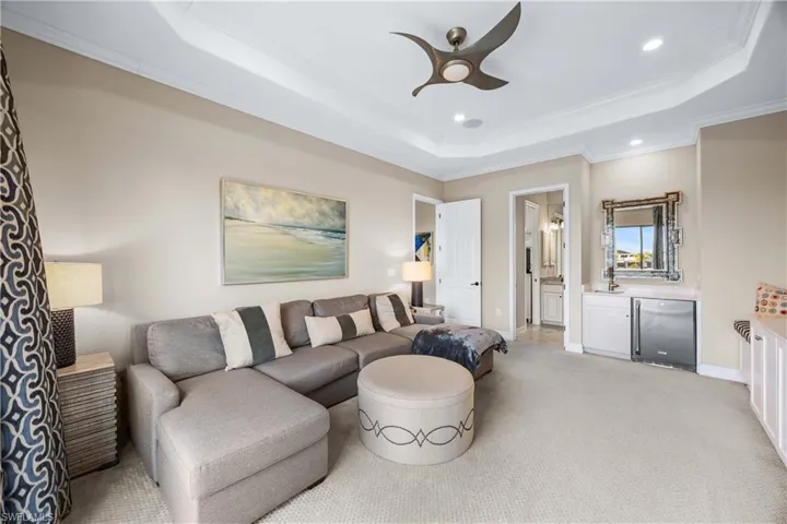 Living room with crown molding, recessed lighting, a raised ceiling, ceiling fan, and light colored carpet
