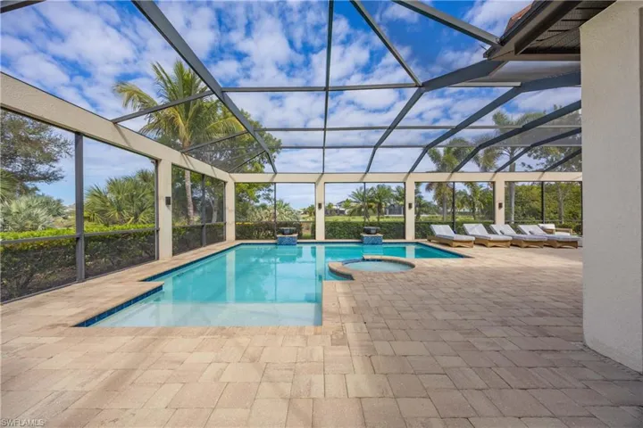 View of pool featuring a lanai, a sunroom, a pool with connected hot tub, and a patio