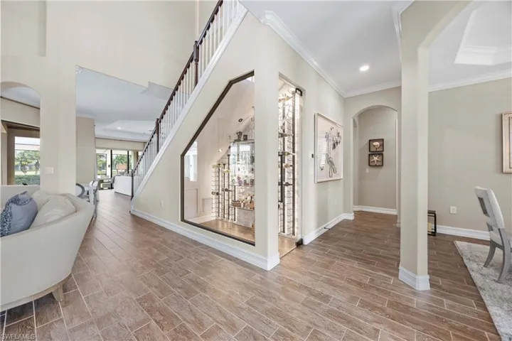 Corridor with arched walkways, crown molding, wood tiled floors, recessed lighting, and stairway