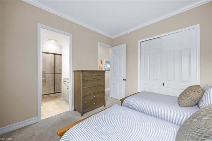 Bedroom with light carpet, ornamental molding, a closet, and arched walkways