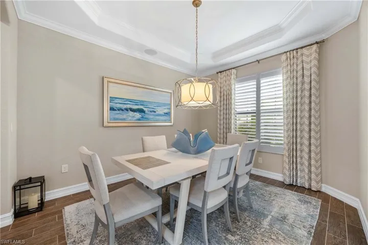 Dining area with wood finish floors, crown molding, and a tray ceiling