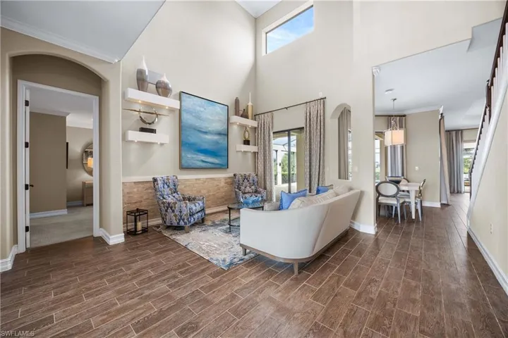 Living area featuring ornamental molding, wood tiled floors, arched walkways, and a high ceiling