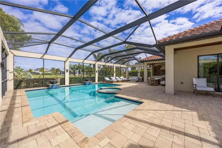 View of pool featuring a sunroom, a patio, glass enclosure, and a pool with connected hot tub