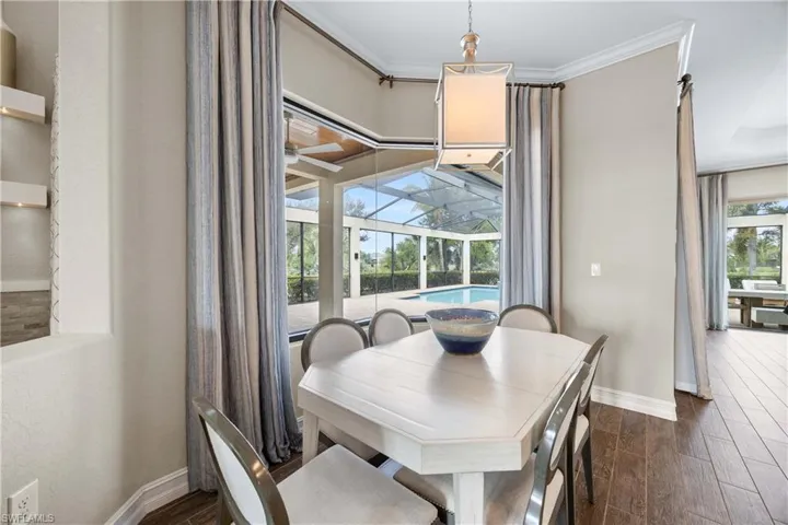 Dining space with a sunroom, wood finish floors, and crown molding